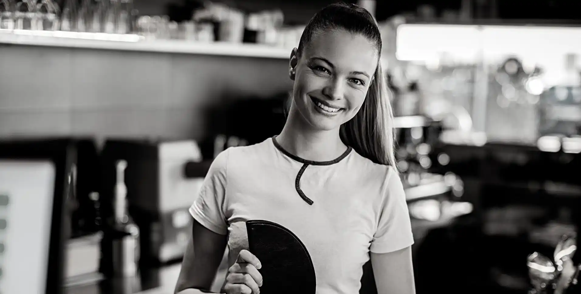 barista, ki pripravlja svežo lokalno praženo kavo ter se smeji in gleda v objektiv kamere