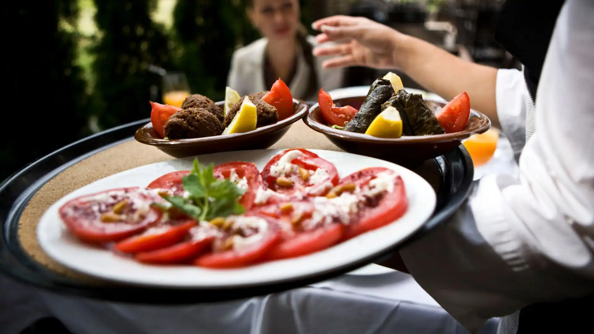 serviranje sveže jedi na poroki v Ljubljani. Na pladnju nosi sezonski finger food, paradižnikovo solato in sarme